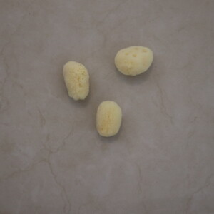 Natural sea sponge trio placed on a beige marble surface highlighting their texture and organic form ideal for eco-friendly bath and skincare routines.