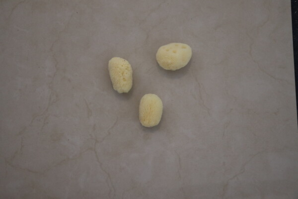 Natural sea sponge trio placed on a beige marble surface highlighting their texture and organic form ideal for eco-friendly bath and skincare routines.