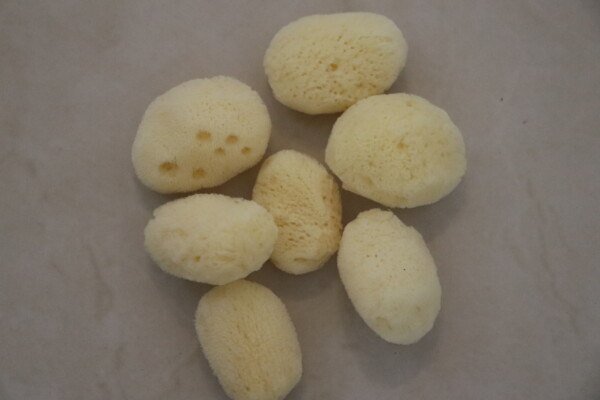 Natural sea sponge on a light surface showcasing texture and size. Perfect for eco-friendly cleaning. Ideal for skincare enthusiasts and organic home care solutions.